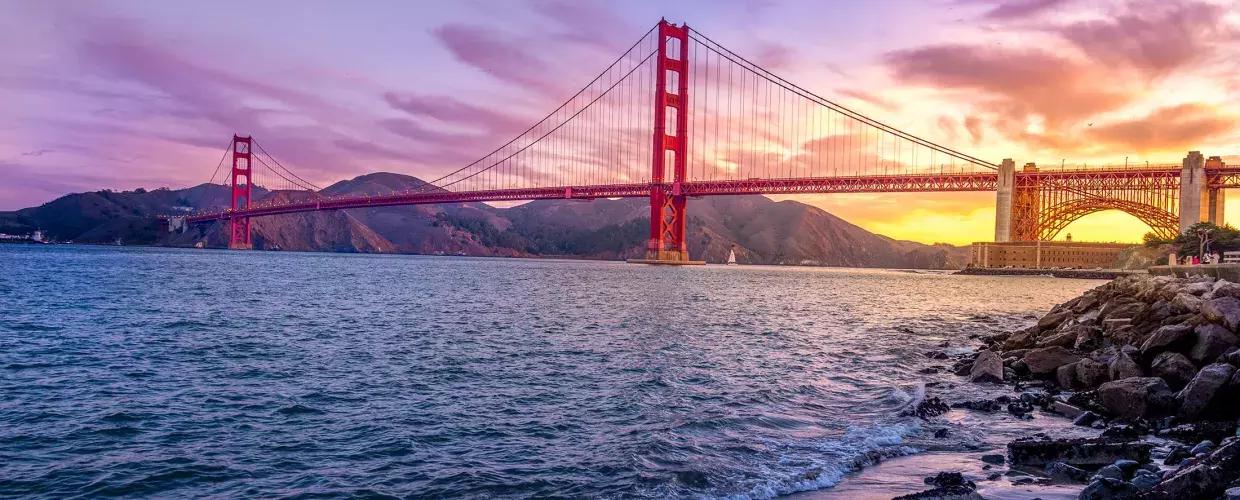 的 金门大桥 at sunset with a multicolored sky 和 的 San Francisco Bay in 的 foreground.